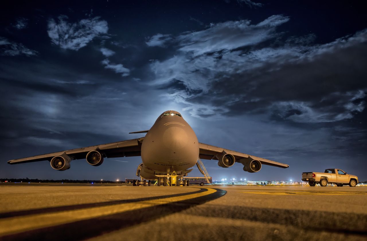 The Art of Drawing Readers In: Your attractive post title goes here A large cargo plane stationed on the tarmac under the night sky, ready for transport.